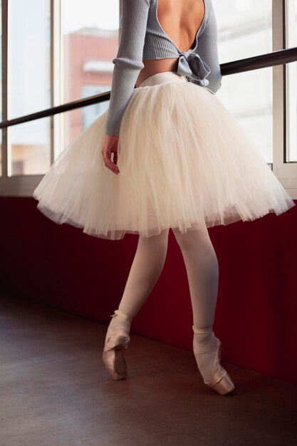 Side view of ballerina in tutu skirt dancing next to window
