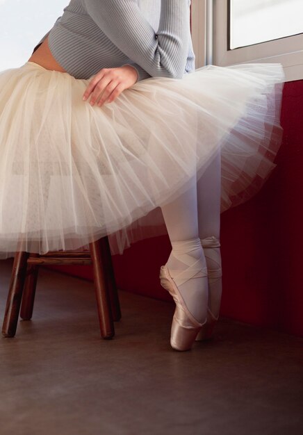 Side view of ballerina in tutu skirt and pointe shoes next to window