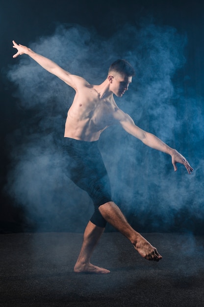 Side view of ballerino dancing in tights with smoke