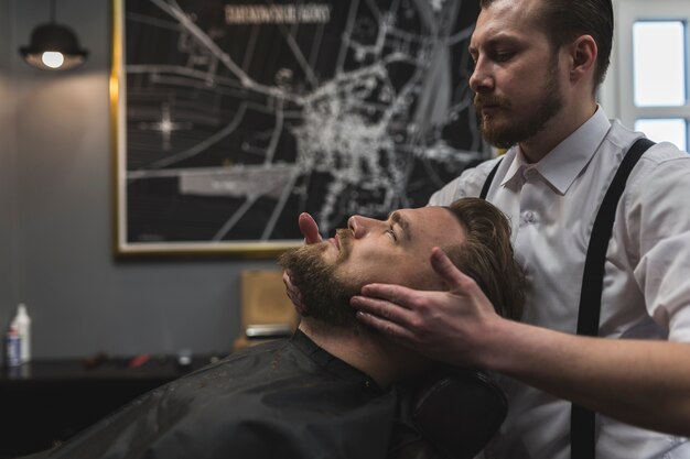 Side view barber styling beard of man