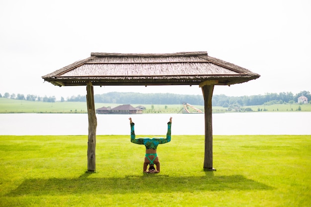 夏の日に公園で逆立ちをしている裸足の若い集中女性の側面図