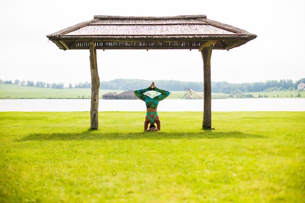 夏の日に公園で逆立ちをしている裸足の若い集中女性の側面図