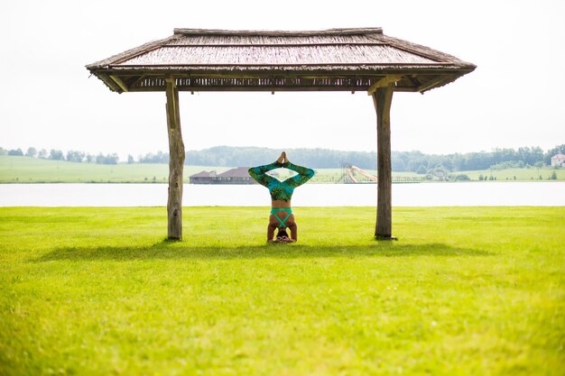 夏の日に公園で逆立ちをしている裸足の若い集中女性の側面図