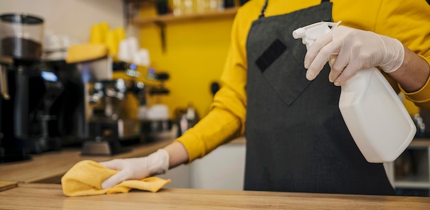 Side view of barista with latex gloves cleaning table