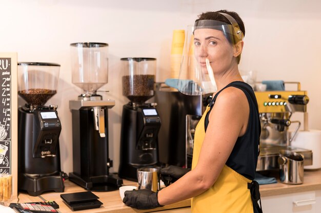 Side view barista at work with face protection