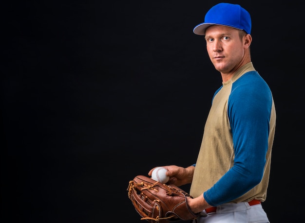 Side view of baseball player posing with ball and glove
