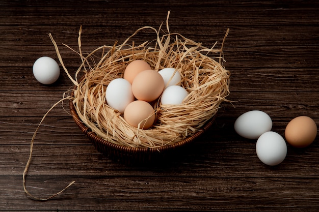 Side view of basket of eggs in nest with eggs around on wooden background