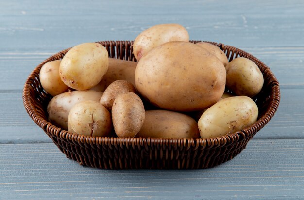 Side view of basket of whole potatoes on wooden background