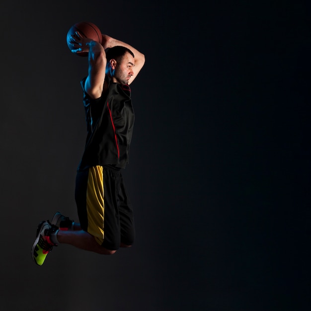 Side view of basketball player dunking with copy space