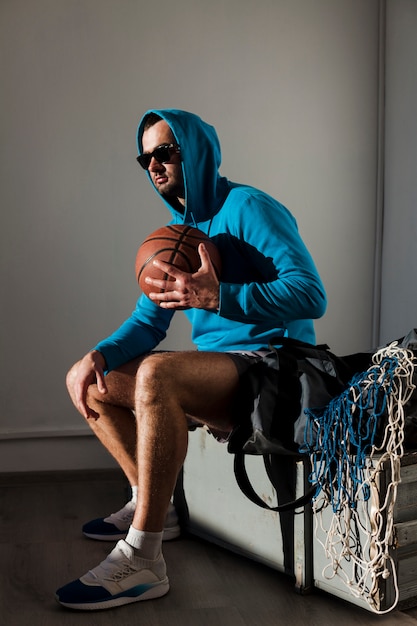 Side view of basketball player posing in hoodie with ball