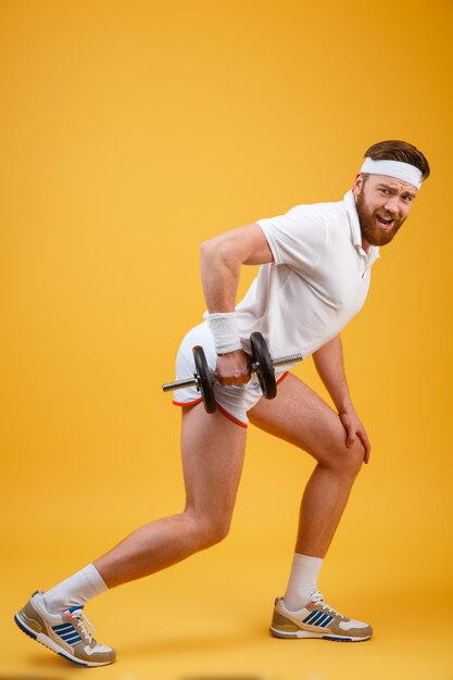 Side view of bearded sportsman doing exercise with dumbbell