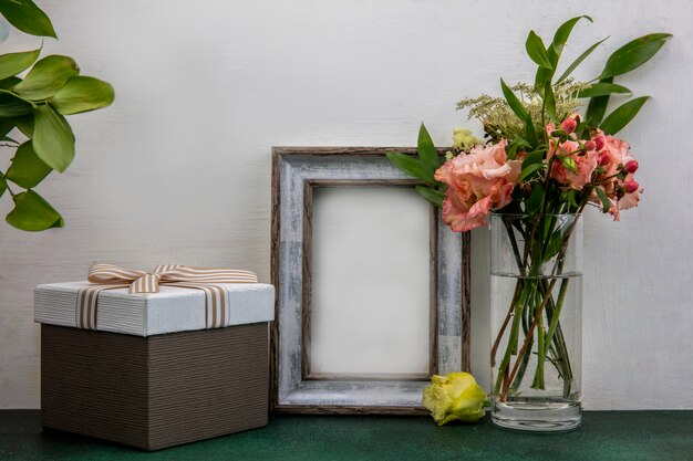 Side view of beautiful and fresh flowers with leaves on a glass on white surface with copy space