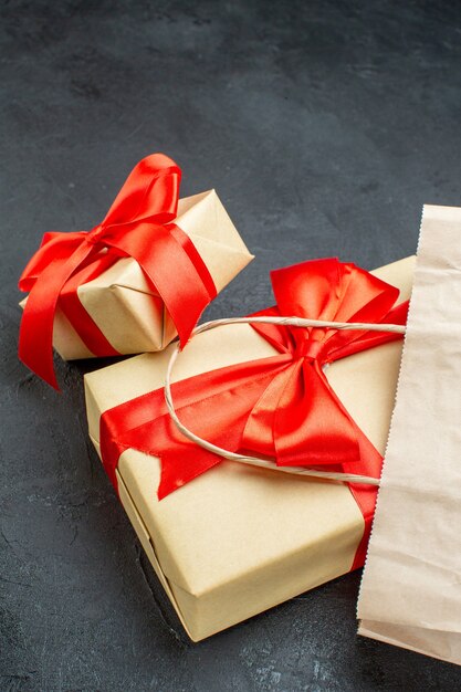 Side view of beautiful gifts with red ribbon on a dark table