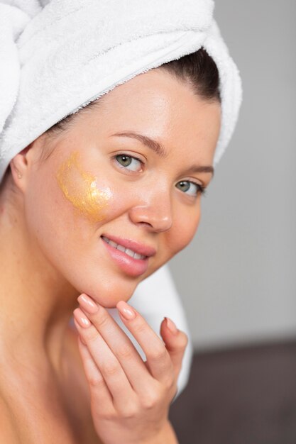 Side view of beautiful woman applying skincare with towel on head