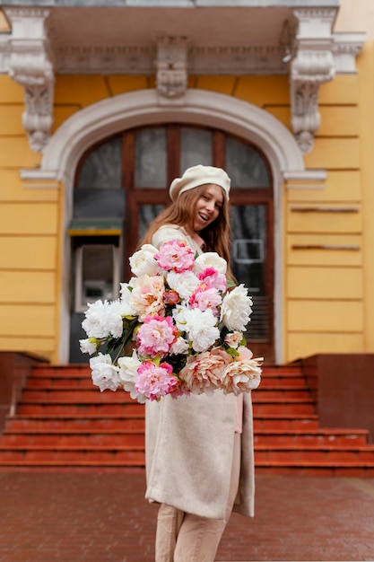 屋外で花の花束を保持している美しい女性の側面図