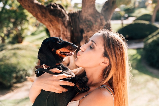 Side view of a beautiful woman kissing her dog