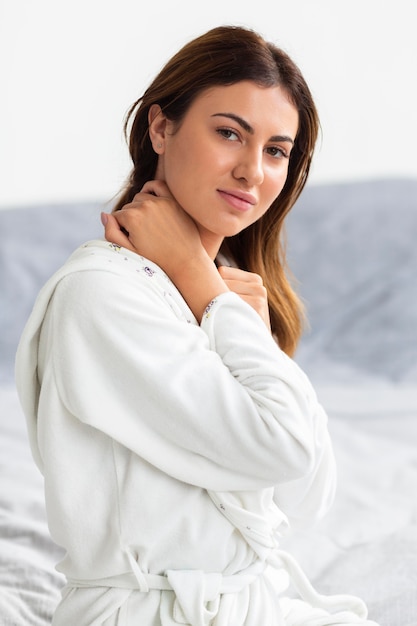 Free photo side view of beautiful woman posing in bathrobe