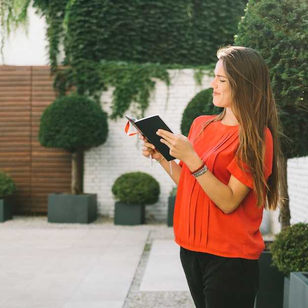 Free photo side view of a beautiful woman reading diary