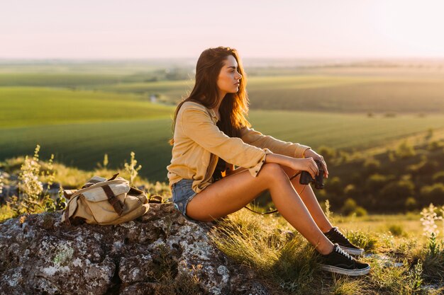 美しい若い女性の岩の上に座っているの側面図