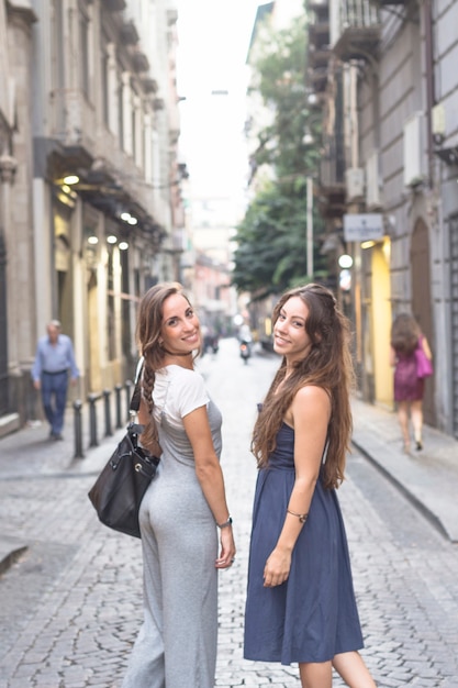 Free photo side view of beautiful young women standing on street