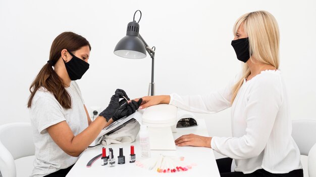 Side view beauty nail worker wearing face mask and gloves