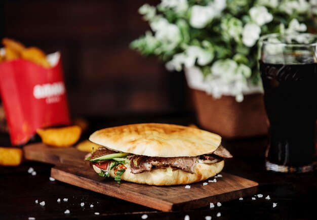 Side view of beef doner kebab in pita bread and on wooden board