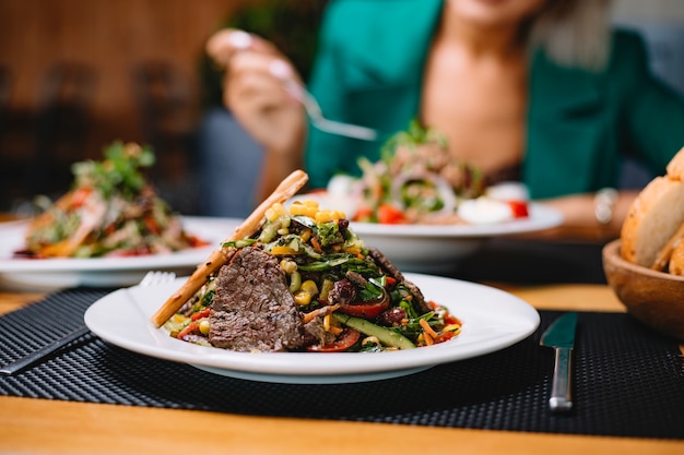 Side view of beef meat salad with vegetables corns and lemon juice in a plate