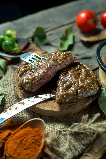 Side view of beef steak with peppercorn sauce on wooden board