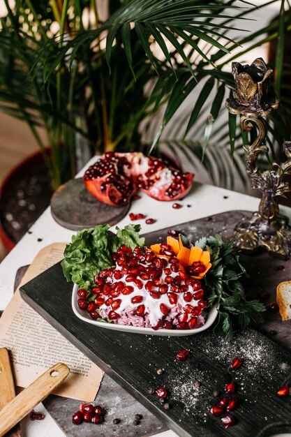 Side view of beetroot salad with sauce mayonnaise and pomegranate on a wooden board