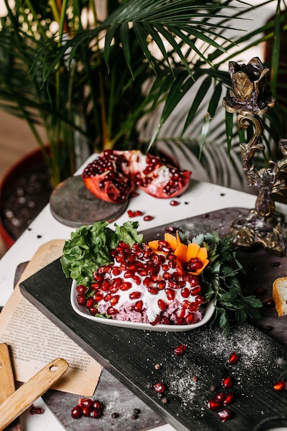 Side view of beetroot salad with sauce mayonnaise and pomegranate on a wooden board