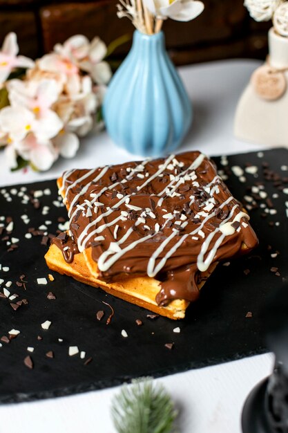 Side view of belgian waffle with chocolate on top on the table