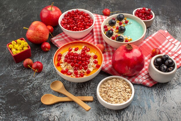 Side view berries pomegranate seeds grapes oatmeal apples candies on the tablecloth spoons