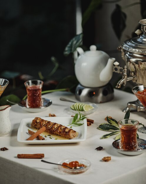 Side view of biscuit roll filled with walnuts served with tea on a table