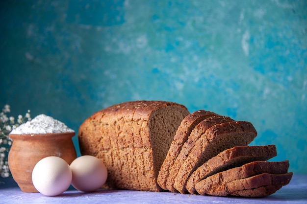 Vista laterale delle fette di pane nero uova di farina su sfondo blu ghiaccio chiaro con spazio libero