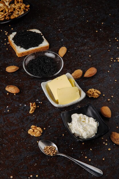 Side view black caviar white bread with cottage cheese black caviar butter almond and walnut on black surface