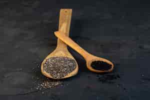 Foto gratuita vista laterale dei semi di cumino neri in cucchiai di legno sul nero