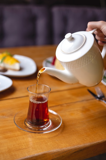 Side view black tea in pear-shape glass on the table