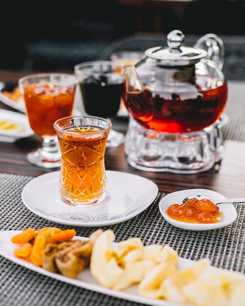 Вид сбоку черный чай с конфетами из белого вишневого варенья и чайника на столе