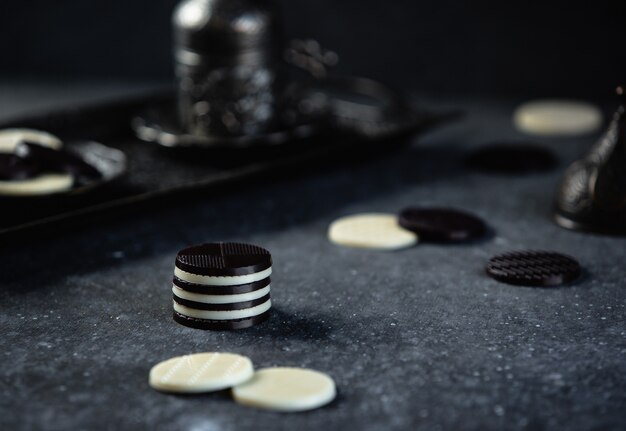 Side view of black and white chocolate candies on dark wall