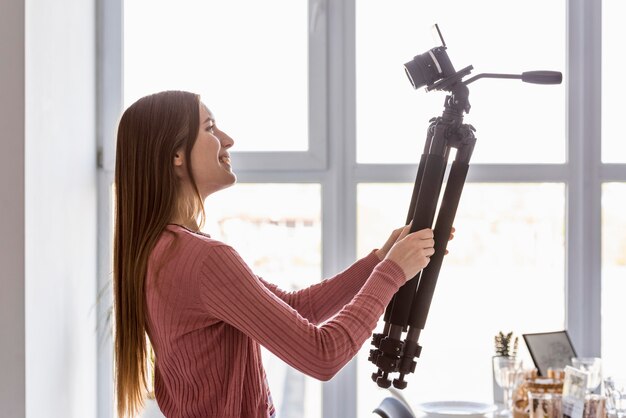 Side view blogger holding tripod up with camera