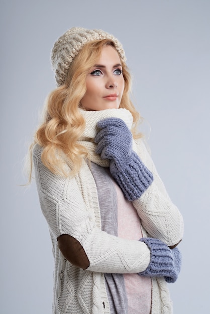 Side view of blond woman in winter clothes dreaming of wam summer