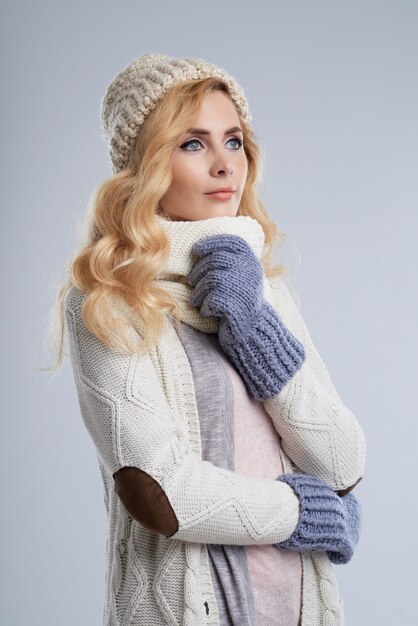 Side view of blond woman in winter clothes dreaming of wam summer