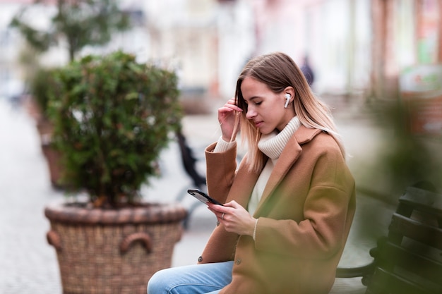 Side view blonde girl listening to music on earphones