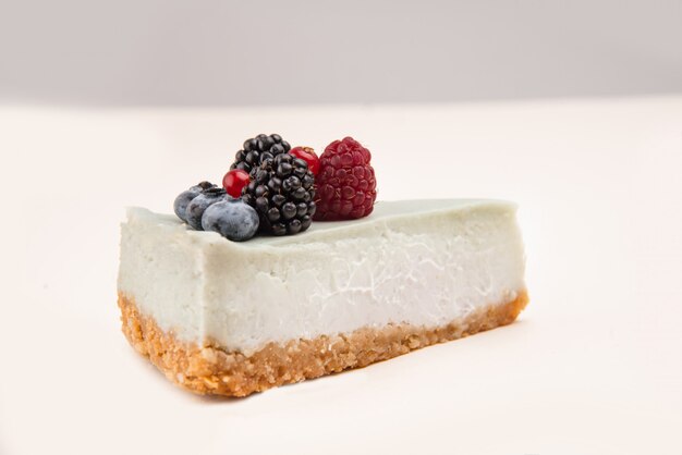 Side view of blue cheesecake with different berries on it isolated over white