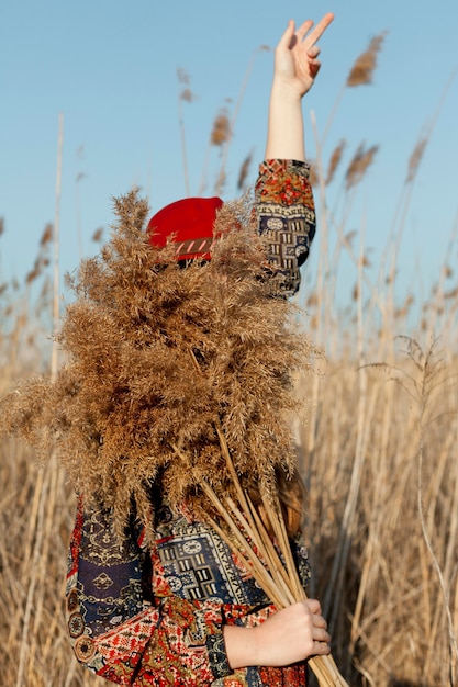 Side view of bohemian woman with face covered by dead grass