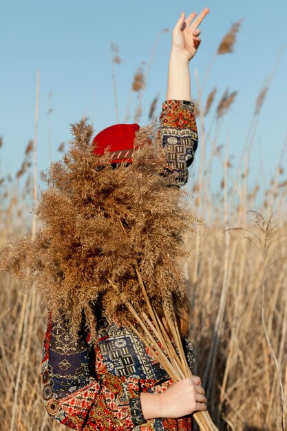 Side view of bohemian woman with face covered by dead grass