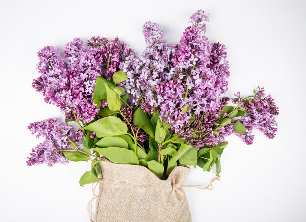 Side view of a bouquet of lilac flowers in a sack on white background