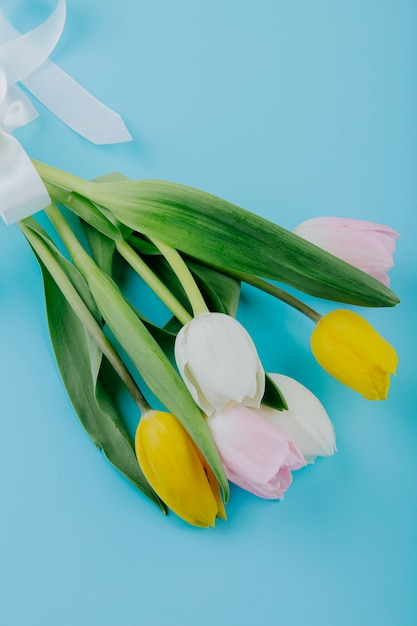 파란색 배경에 고립 된 흰색 노란색과 분홍색 컬러 튤립 꽃의 꽃다발의 측면보기