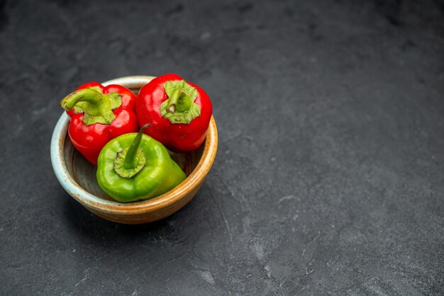 Side view of bowl of bell peppers on the left side on dark green table