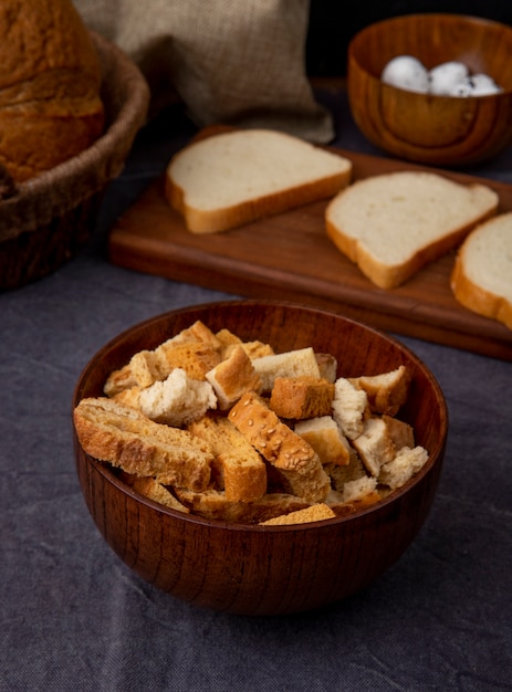 Free photo side view of bowl of bread pieces on maroon background